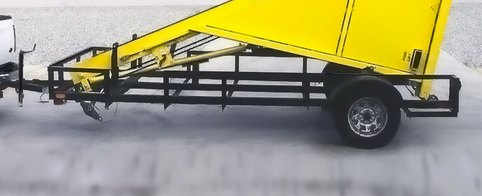 The Dumper on its Trailer, ready for transportation along roadways. Its Hydraulic Ram System quickly loads/unloads it.