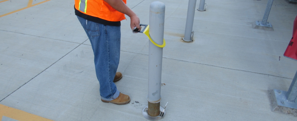 Construction Worker using a Hartman Bollard Lifter to lift a 4" removable pipe bollard with ease, using only one hand